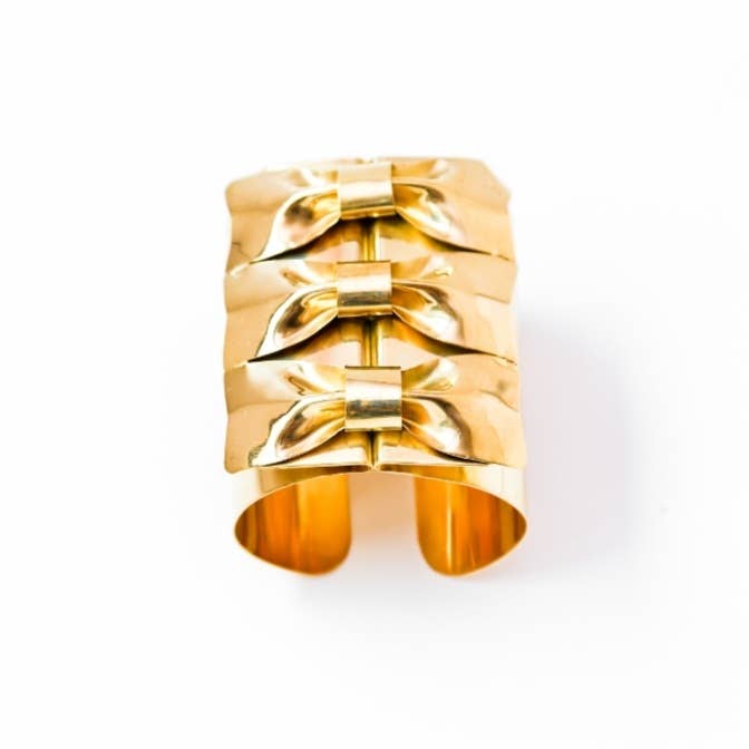 Brass triple bow tie cuff bracelet on white background