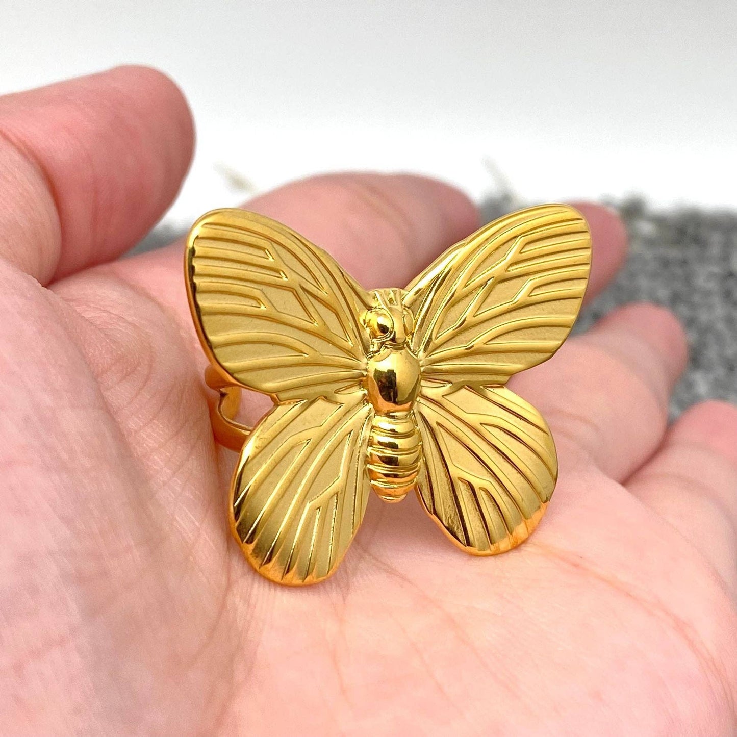 gold butterfly cocktail ring in the palm of a hand