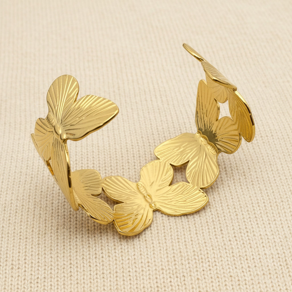 the underside view of a gold butterfly cuff bracelet on an ivory fabric background