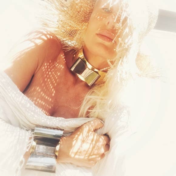Woman wearing brass and collar necklace with bow motif and white tank top