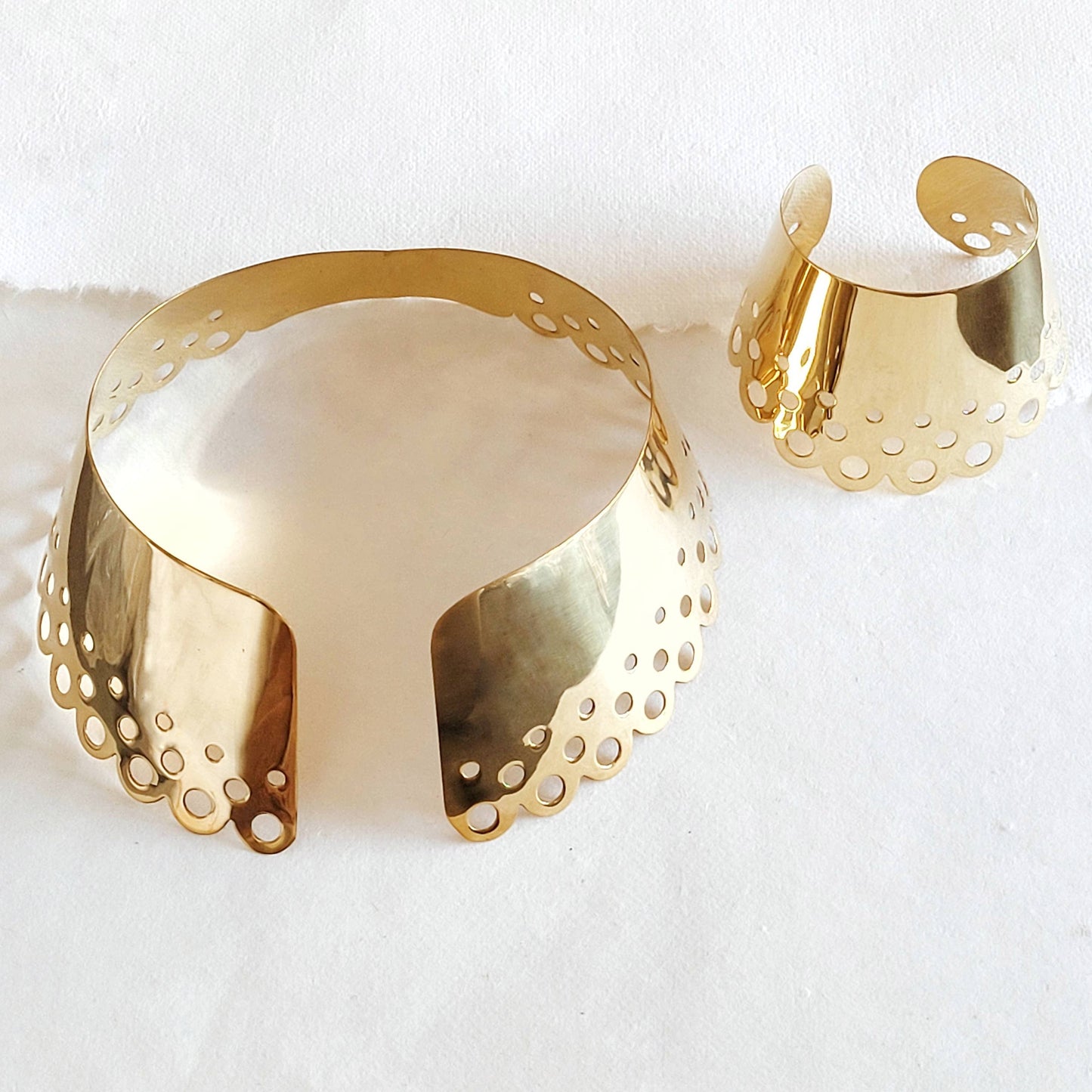 Brass scallop collar necklace and cuff with circular cutouts against a white background