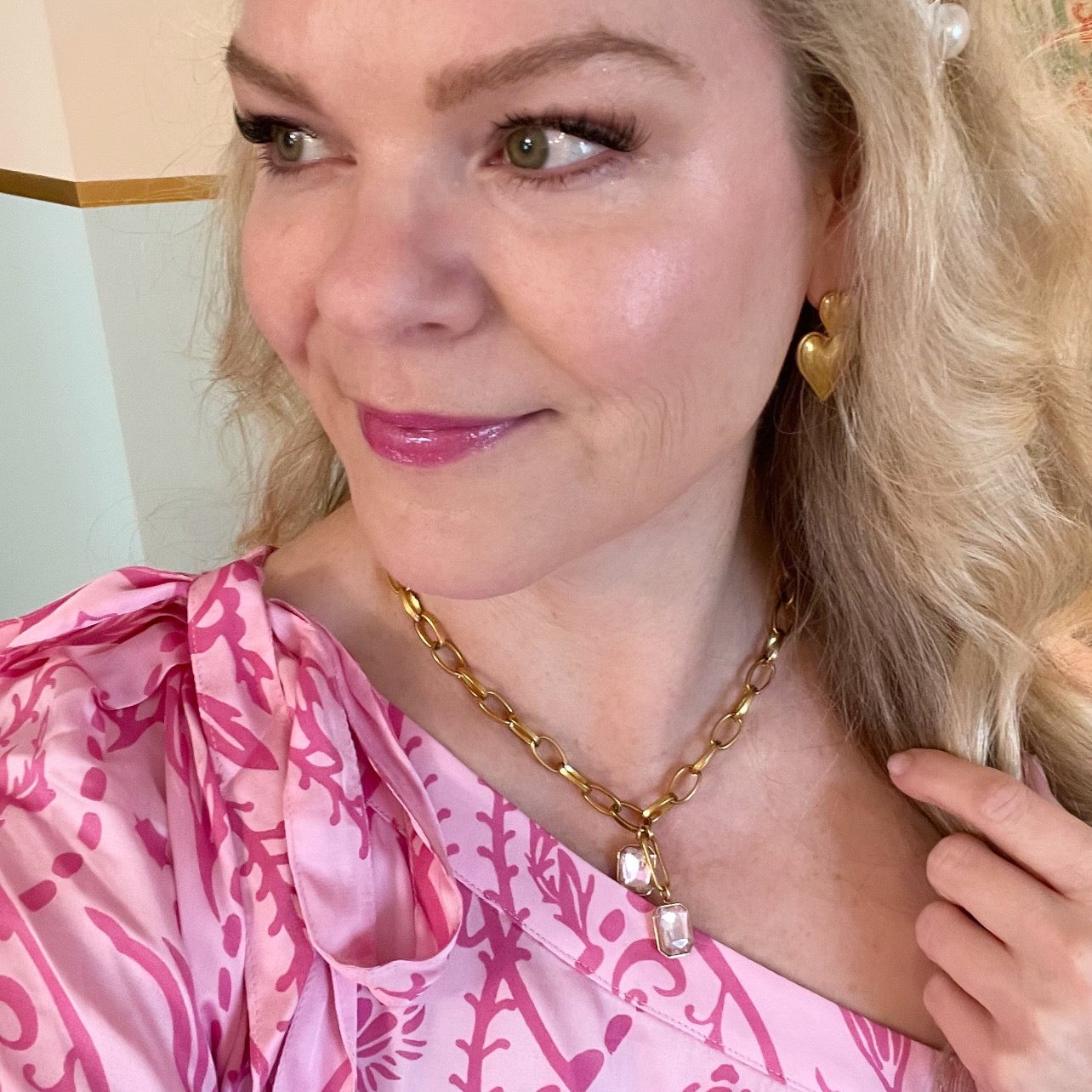 woman wearing gold pendant chain necklace with two pink crystals and pink dress