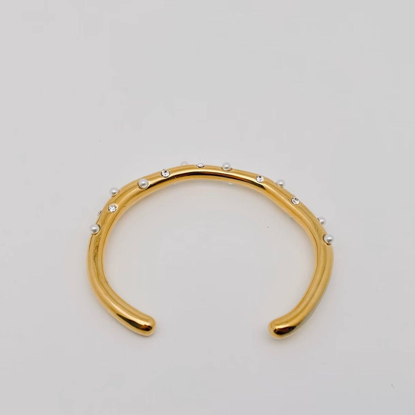 Gold pearl and rhinestone cuff bracelet flat lay showing full open bangle design