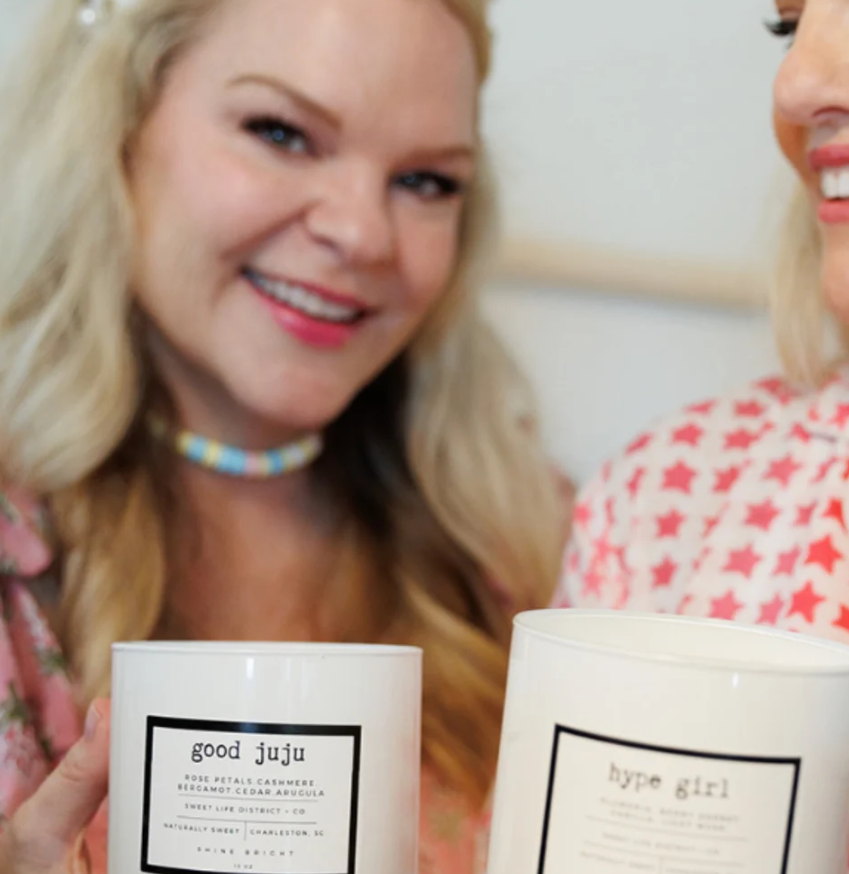 Two women holding candles in their hands in a an indoor setting