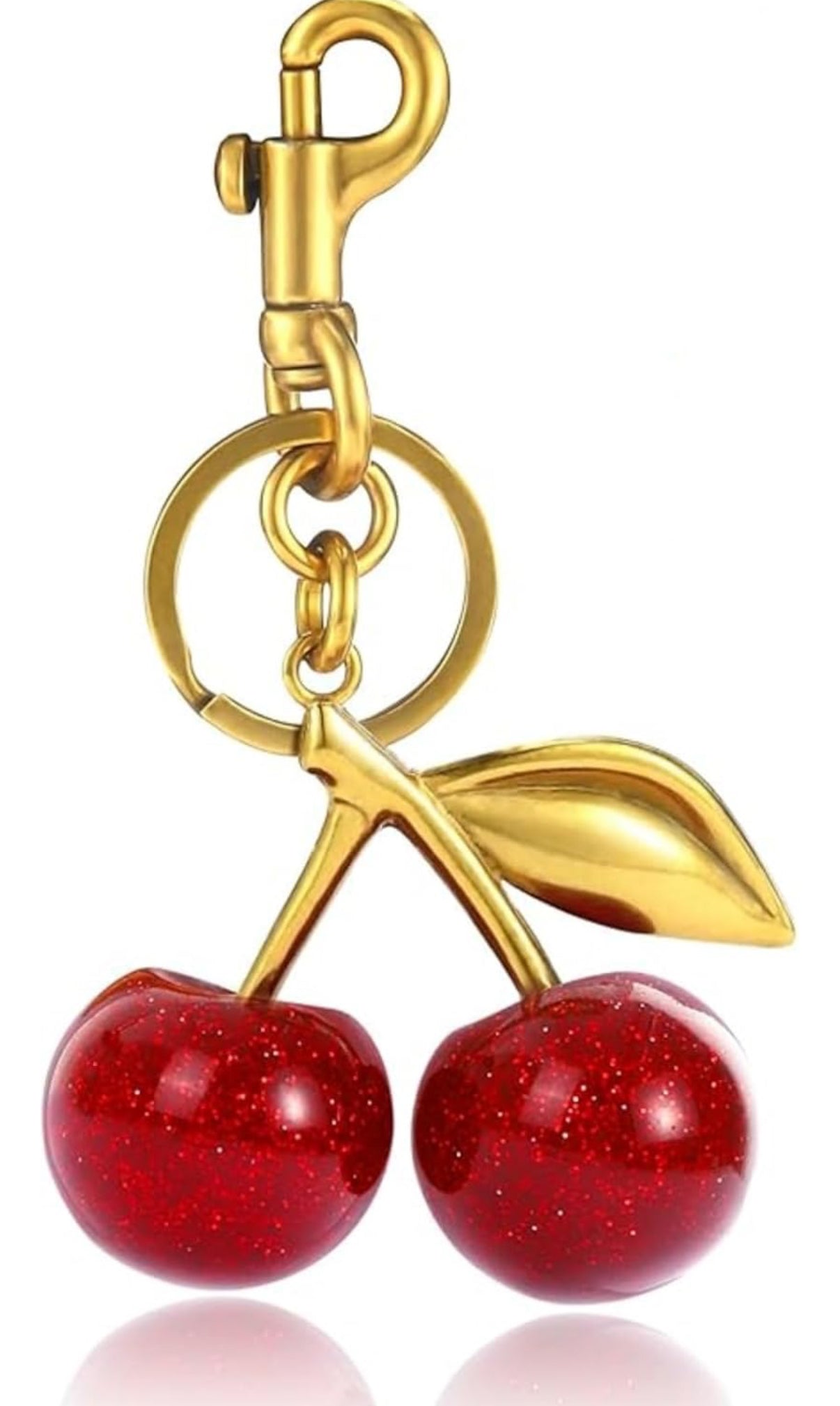 Gold keychain with red cherry design on a white background