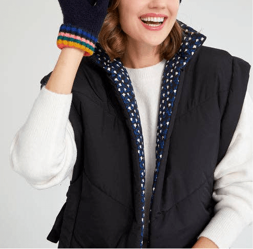 woman wearing black reversible vest with white long sleeve top and gloves against a white background