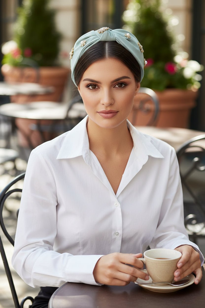 a woman wearing a white shirt and light blue headband with crystals on it in an outdoor cafe setting