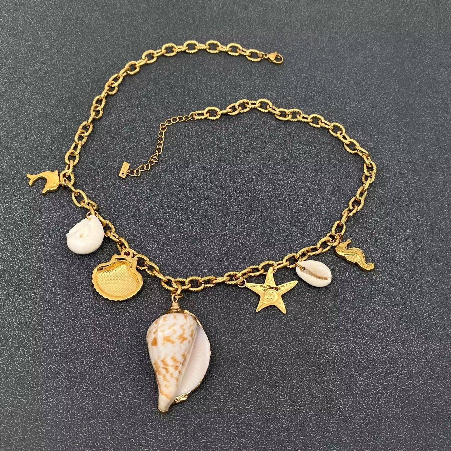 back view of coastal themed multi charm necklace on gold chain and 7 charms with central conch shell