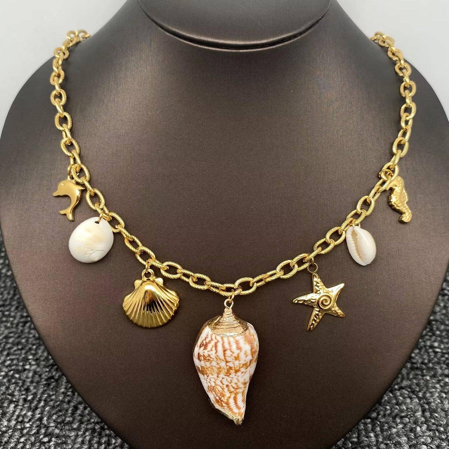gold multi charm coastal themed charm necklace with 7 charms and a central conch shell