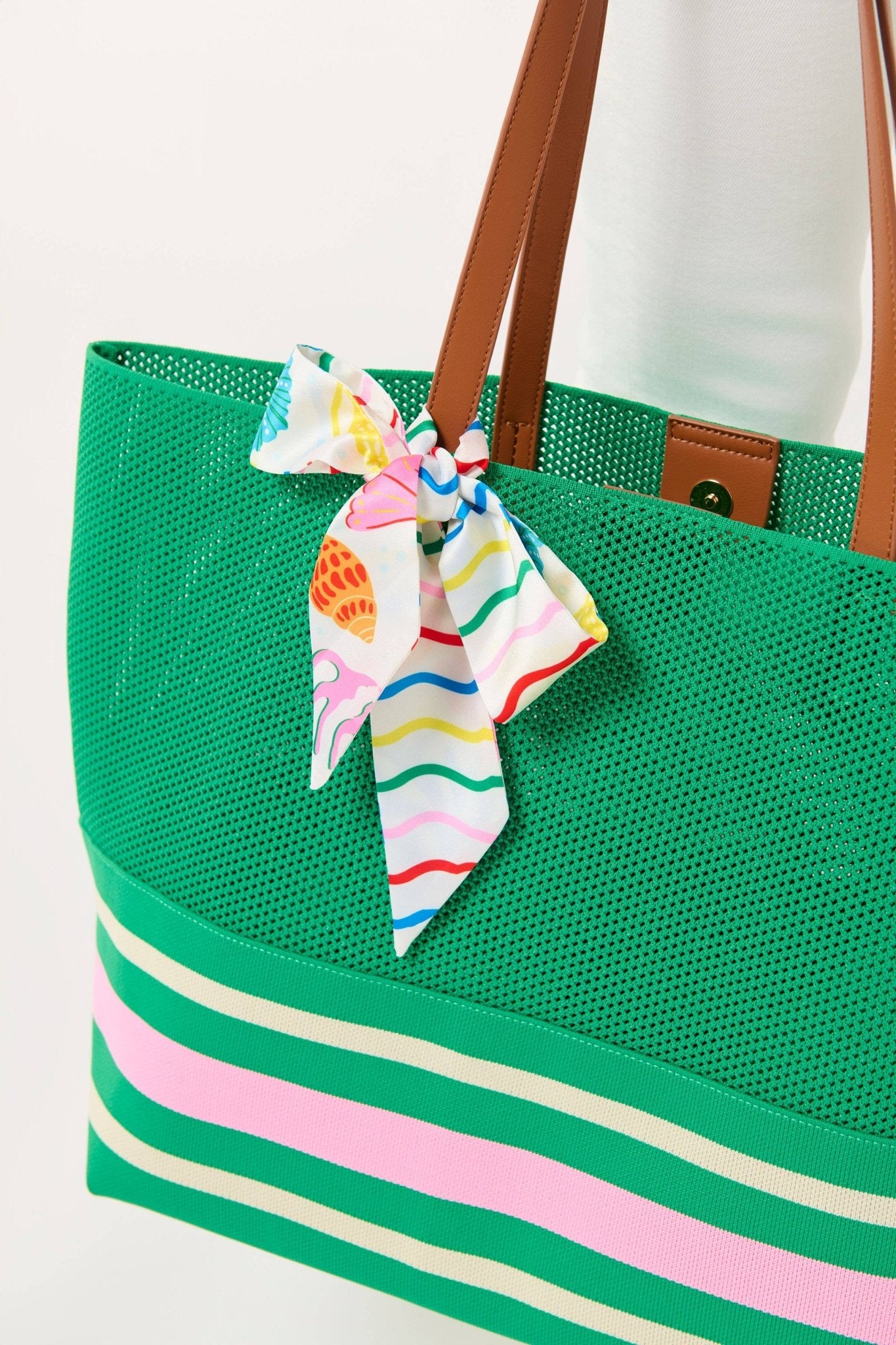 Green tote bag with striped base and colorful scarf, on a white background