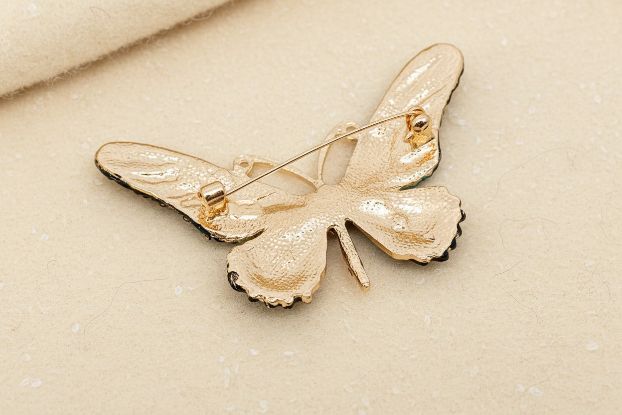 Back view of a crystal encrusted butterfly brooch to show the pin closure on a white background