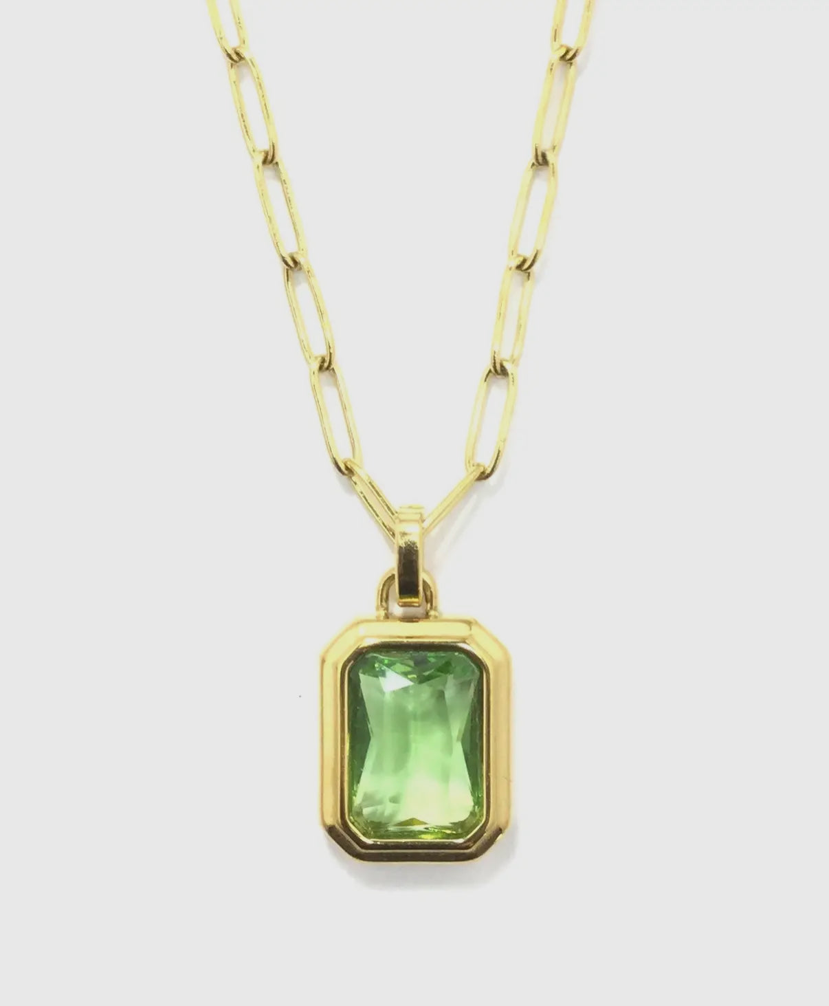 close up of emerald colored stone set in gold against a white background