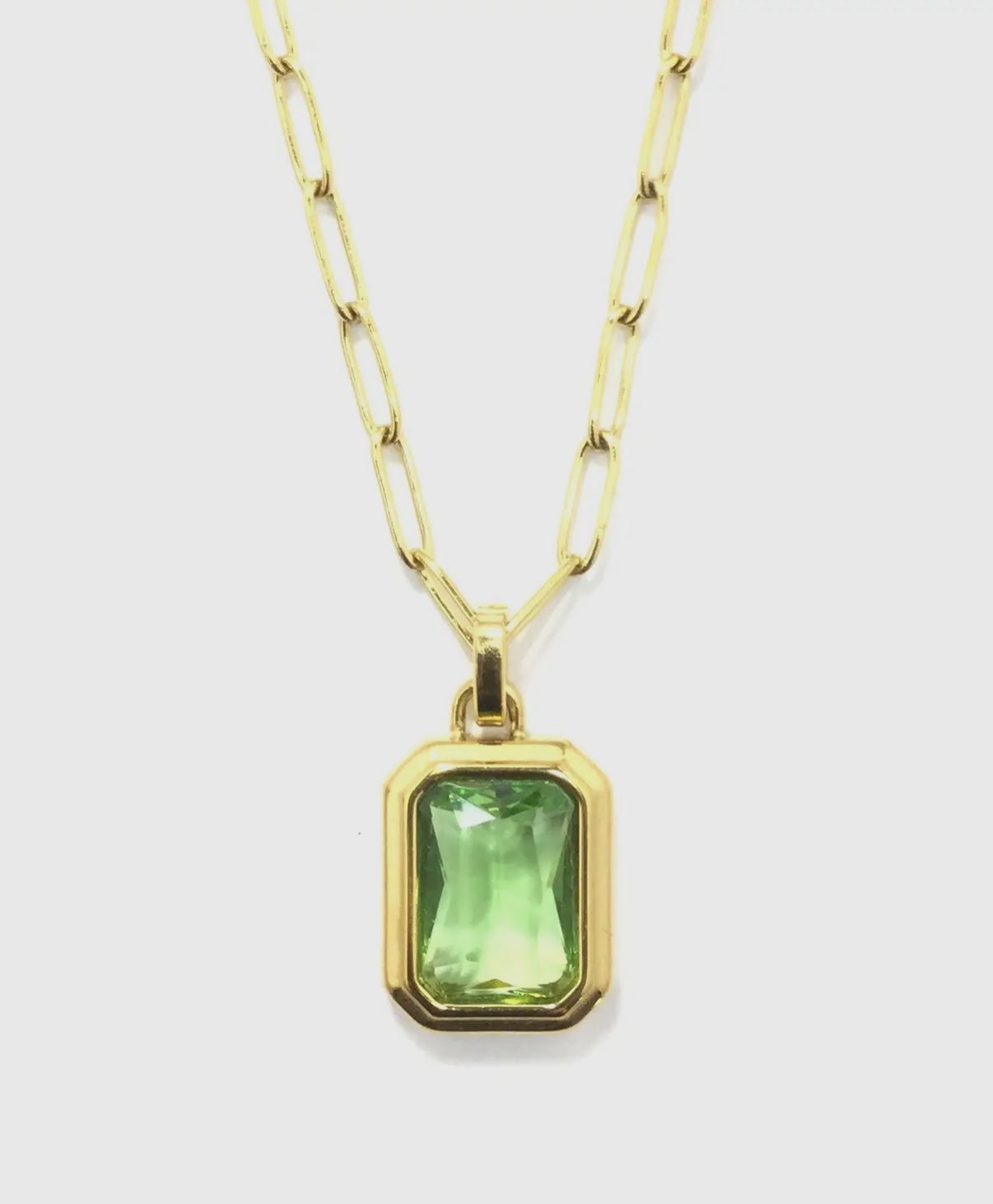 close up of emerald colored stone set in gold against a white background