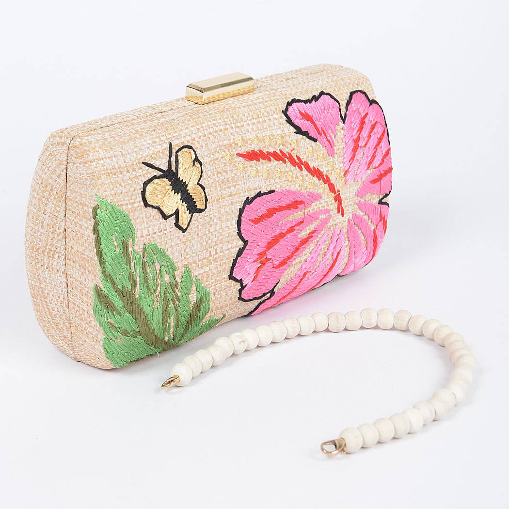 raffia purse with butterfly and floral embroidery, gold top closure, and removable wooden bead handle against a white background