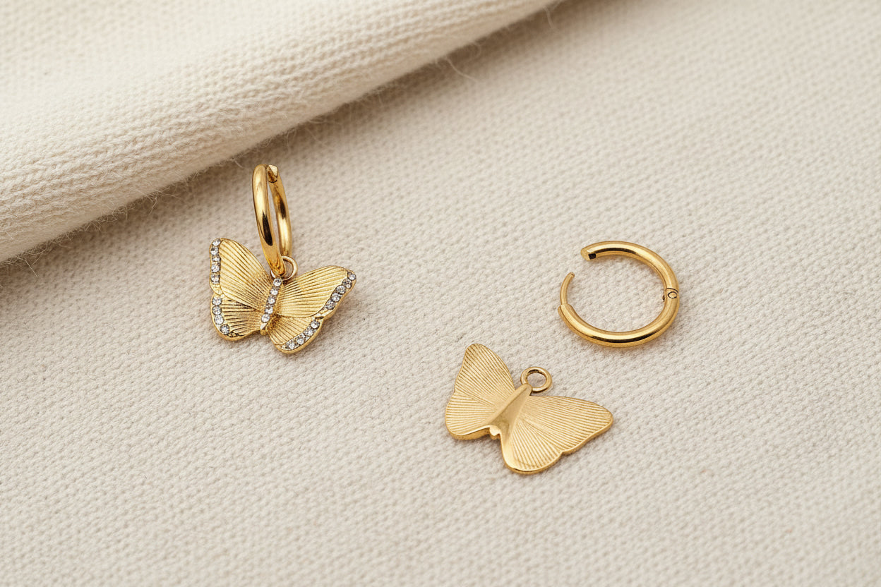 Front and back view of gold butterfly crystal earrings on a dark textured surface