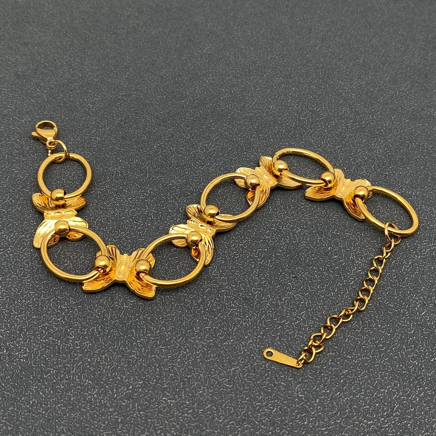 back view of gold butterfly link bracelet against a grey background