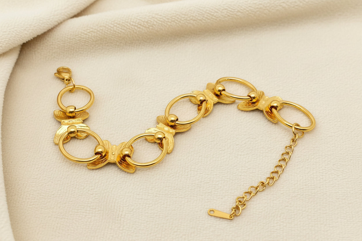 back view of gold butterfly link bracelet against an ivory background