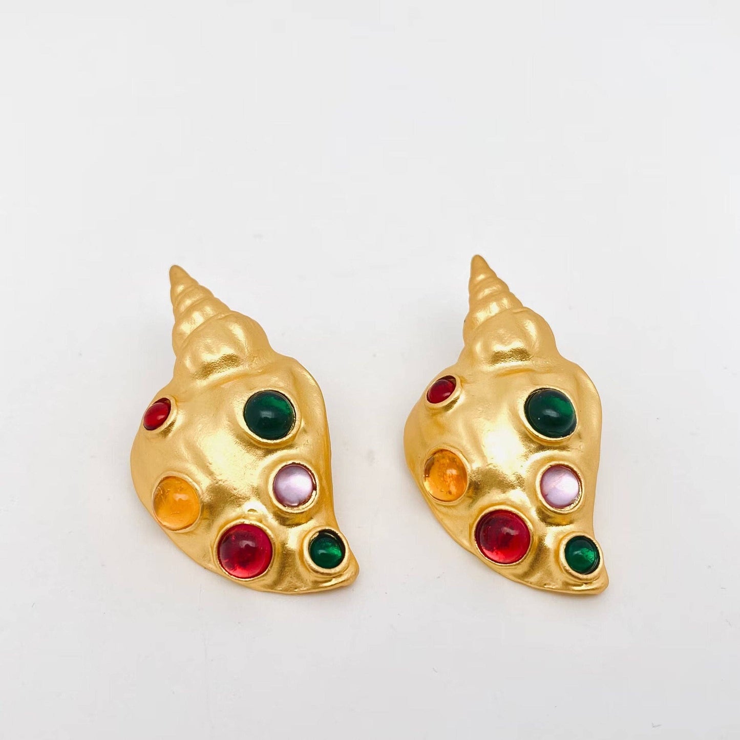 gold conch earrings with inlaid multi-colored glass against a white background
