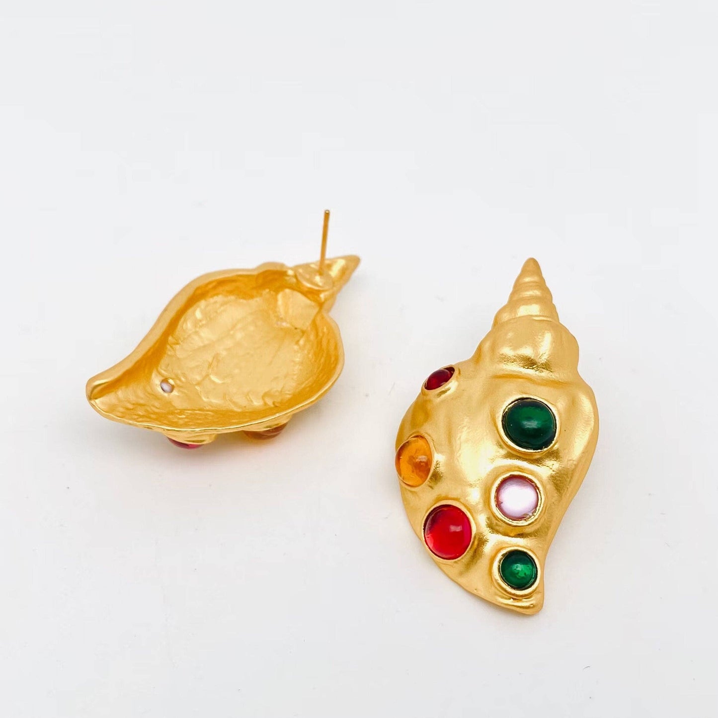view of front and back of pair of gold conch shaped earrings with inlaid multi-colored glass stones against a white background