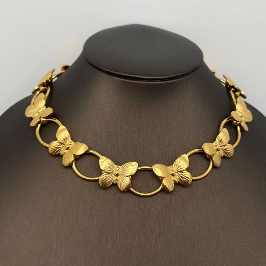 gold necklace with butterflies and circle links on a black necklace stand