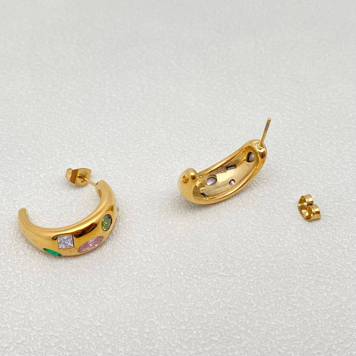 the side and back view of a pair of gold multi color inlaid crystal hoop earrings against a white background
