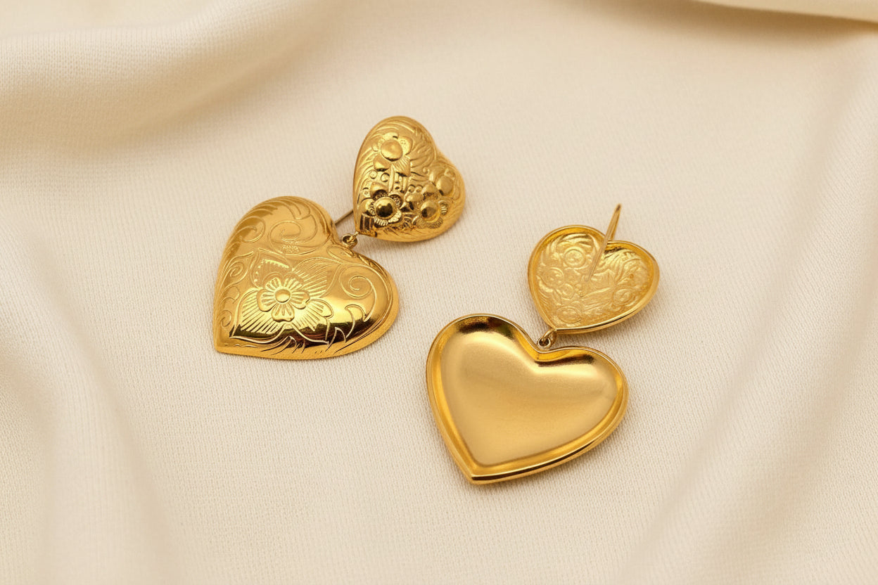 front and back view of pair of gold embossed double heart earrings against an ivory fabric background