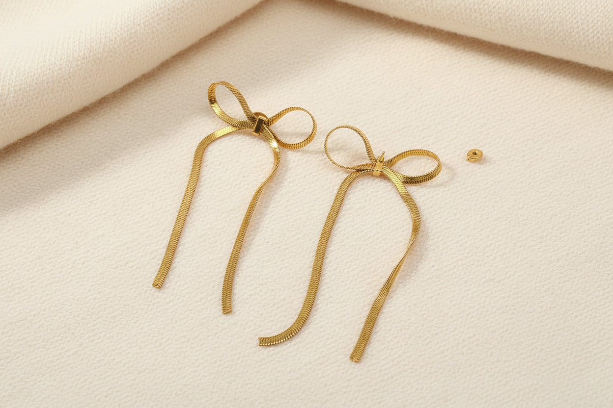 gold chain bow earrings on a black background