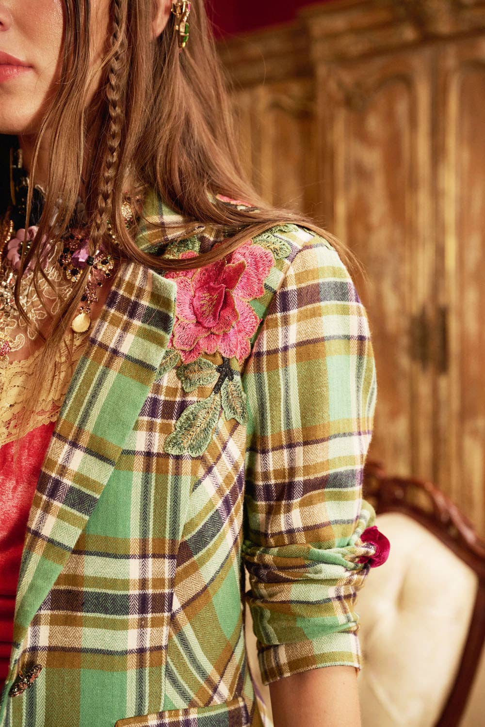 up closer shoulder detail of woman wearing green plaid blazer with floral embroidery
