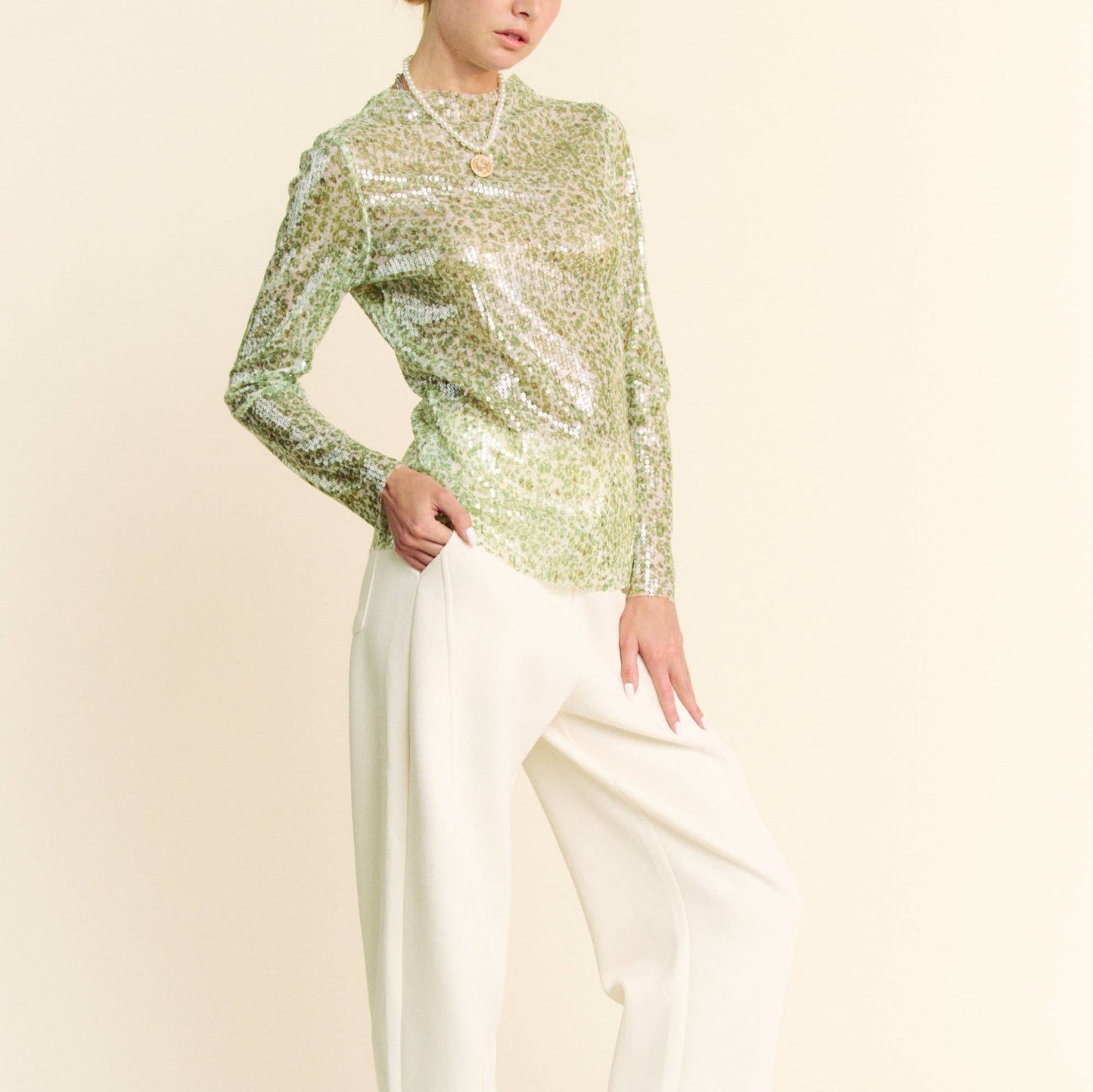 woman wearing a green sequin top with white pants