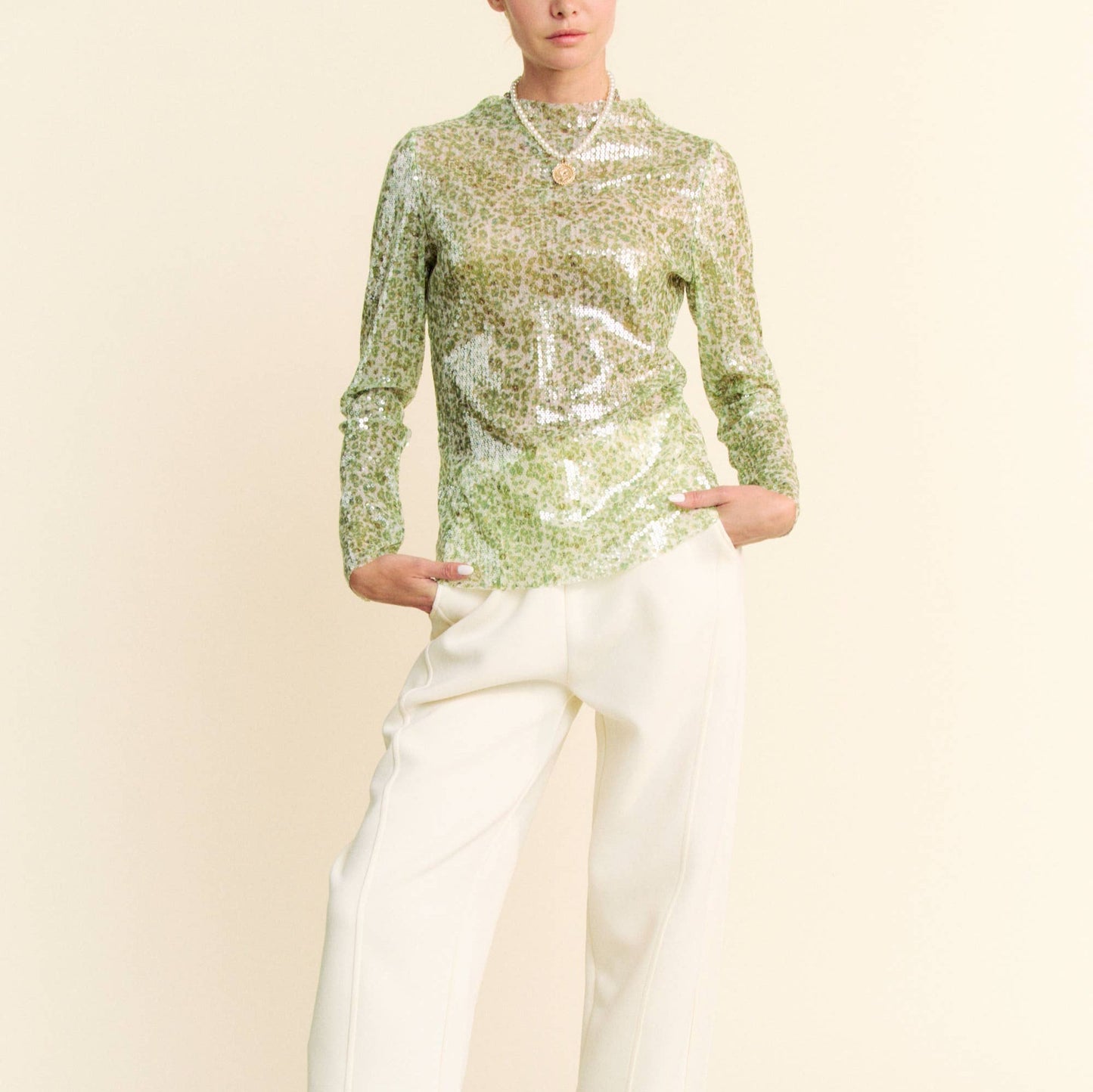 woman wearing a green sequin top and white pants