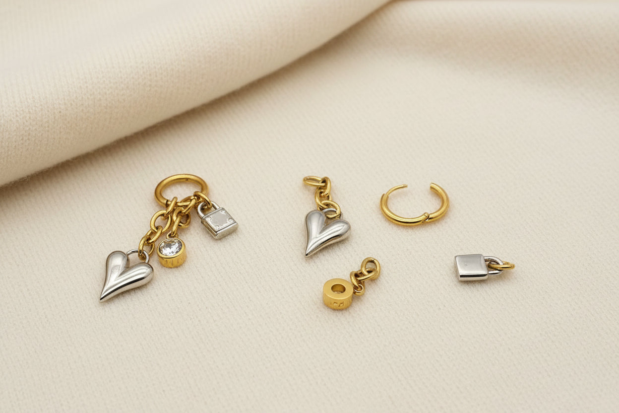 gold and silver heart, lock, and crystal charm earrings on an ivory fabric background