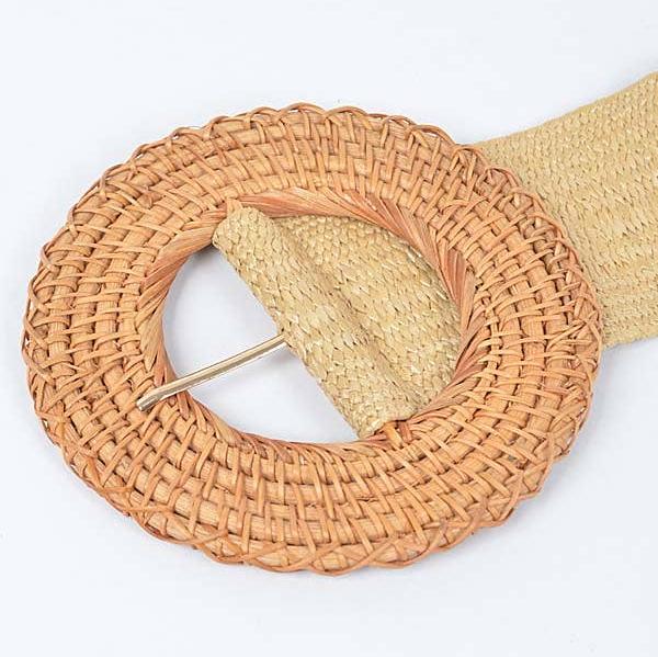 up close view of tan round rattan belt buckle against a white background