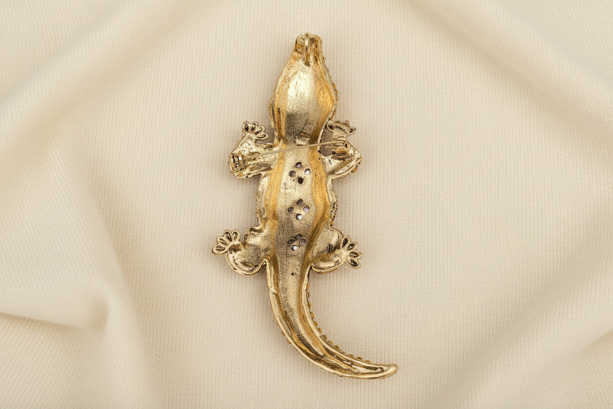 back view of gold crocodile-shaped brooch on a gray background