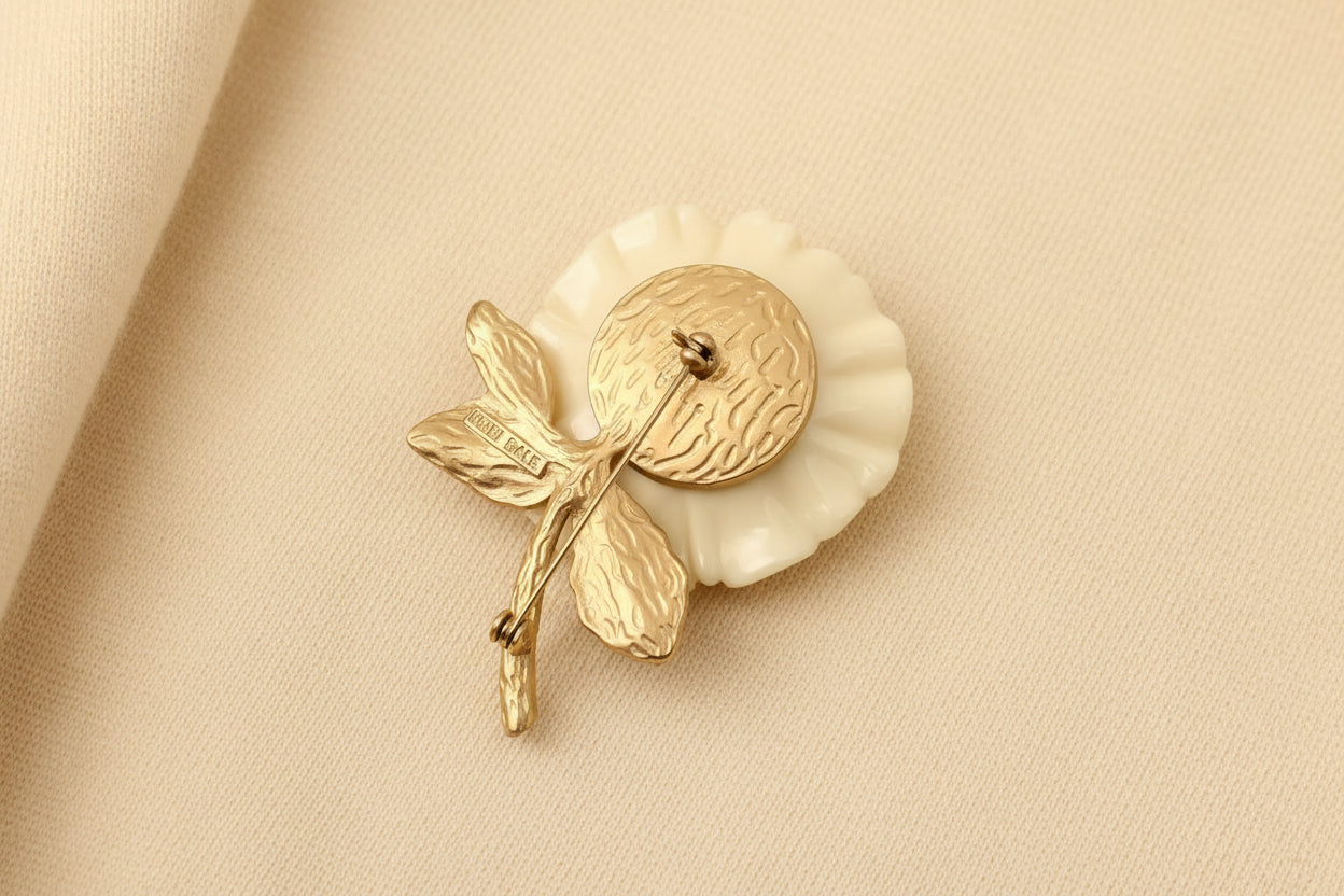Gold and white brooch on a dark gray background