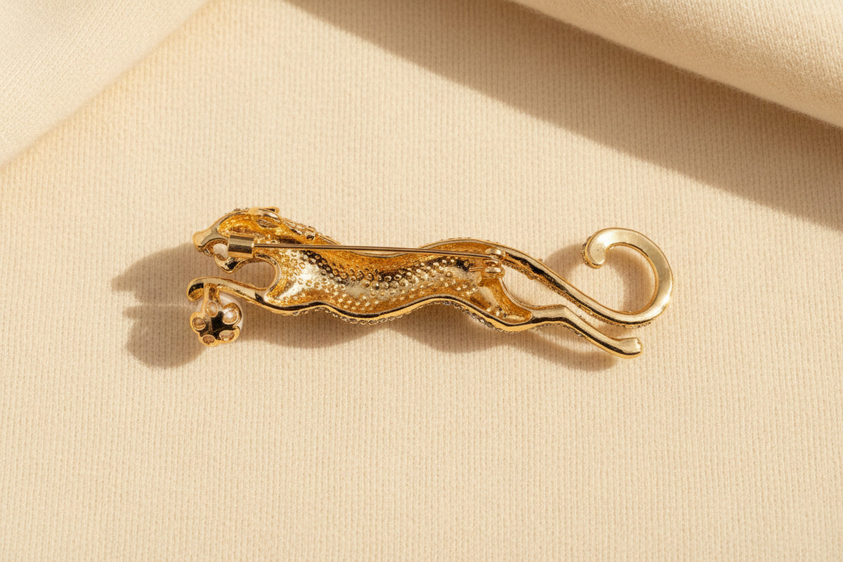 Back view of leopard brooch in gold color on a gray textured background