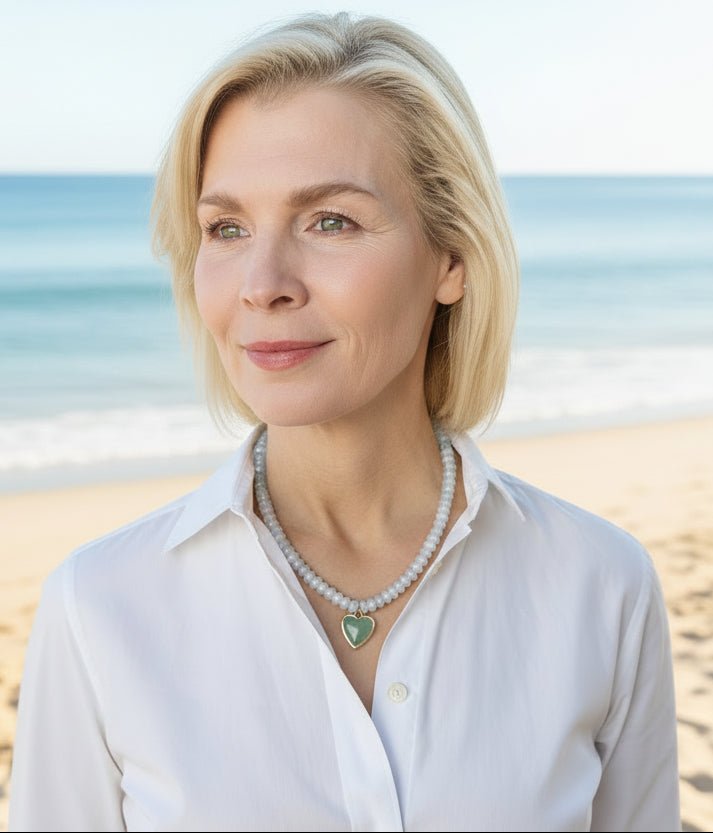 Woman wearing a white shirt and a gemstone beaded necklace with a heart pendant.