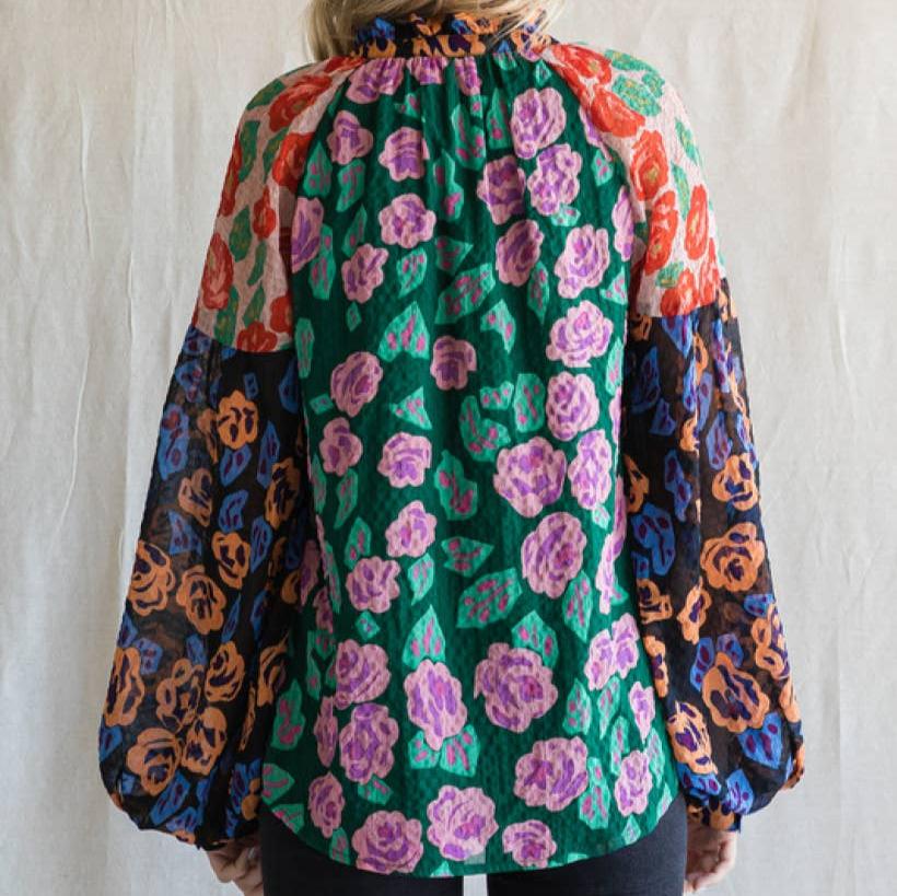 back view of a woman wearing a floral print blouse against an ivory background
