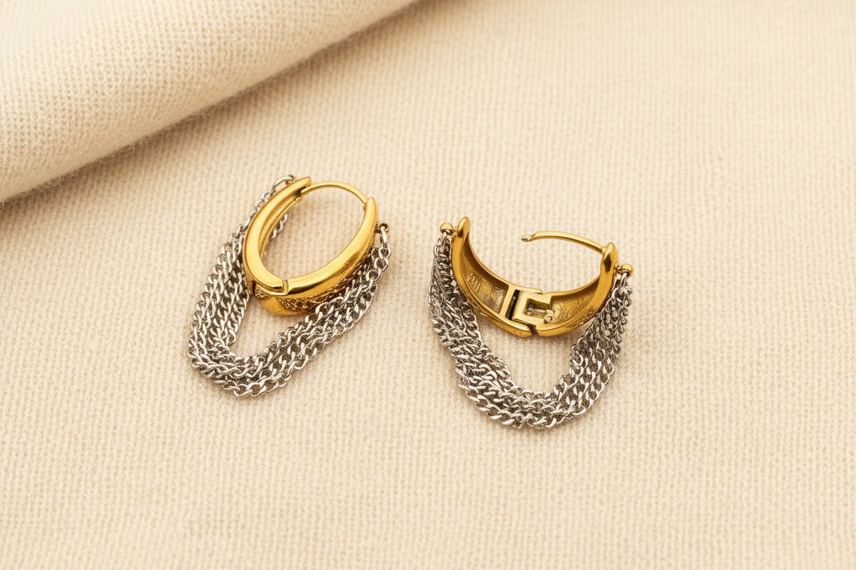Gold and silver hoop earrings with chain details on an ivory surface