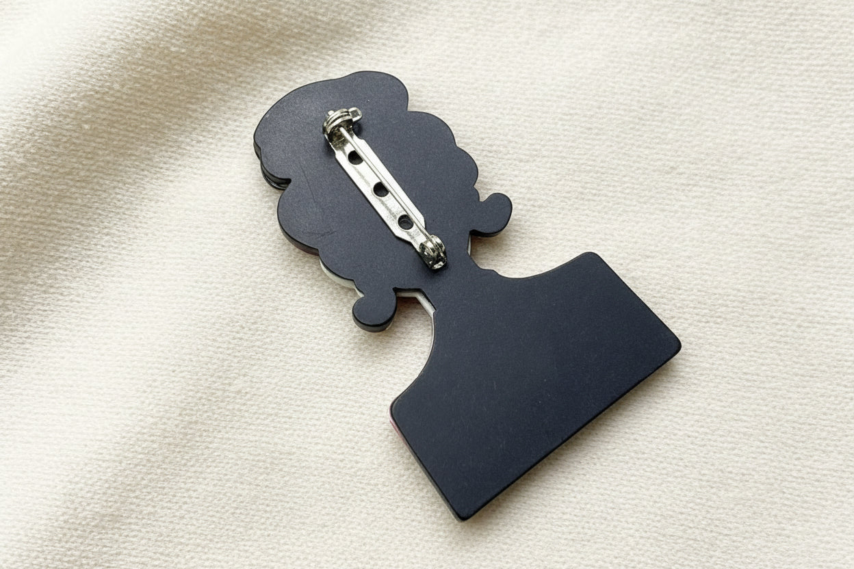 Back view of a silhouette of a person brooch to show pin closure on a textured gray background