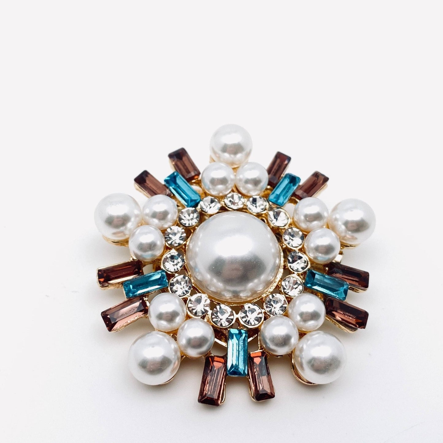 Decorative brooch with pearls and gemstones on a white background