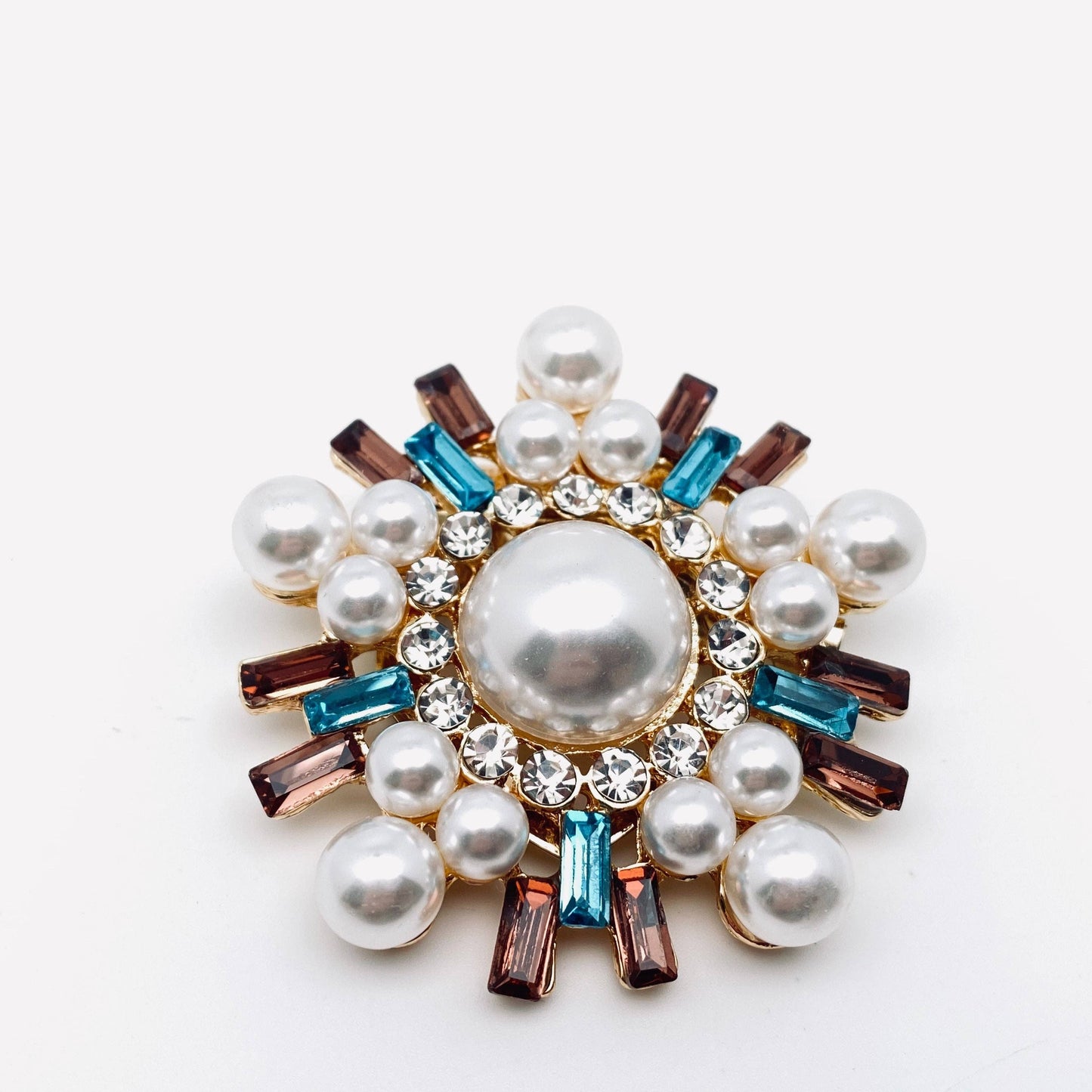 Decorative brooch with pearls and gemstones on a white background