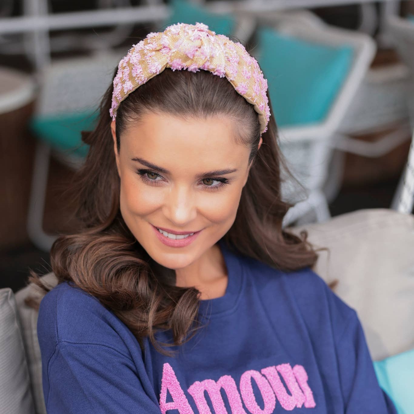 woman in navy top wearing pink and tan raffia heaband