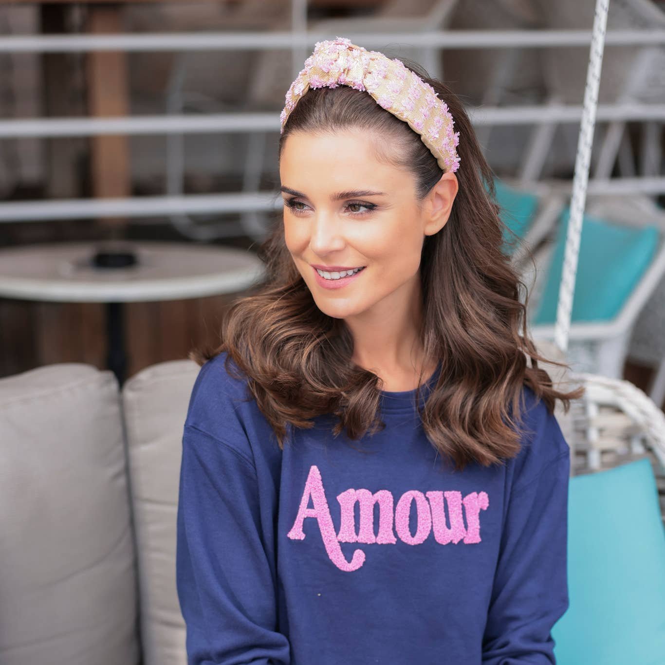 woman in navy shirt with the words "Amour" written on the front and pink and tan raffia headband