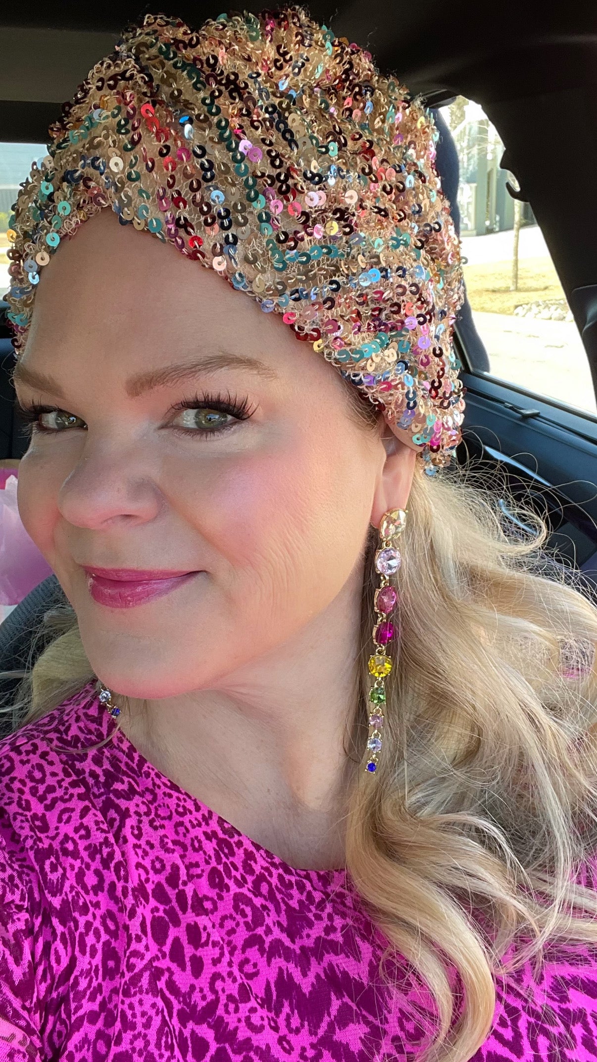 a woman with blonde hair and pink dress and sequin turban wearing rainbow crystal drop earrings