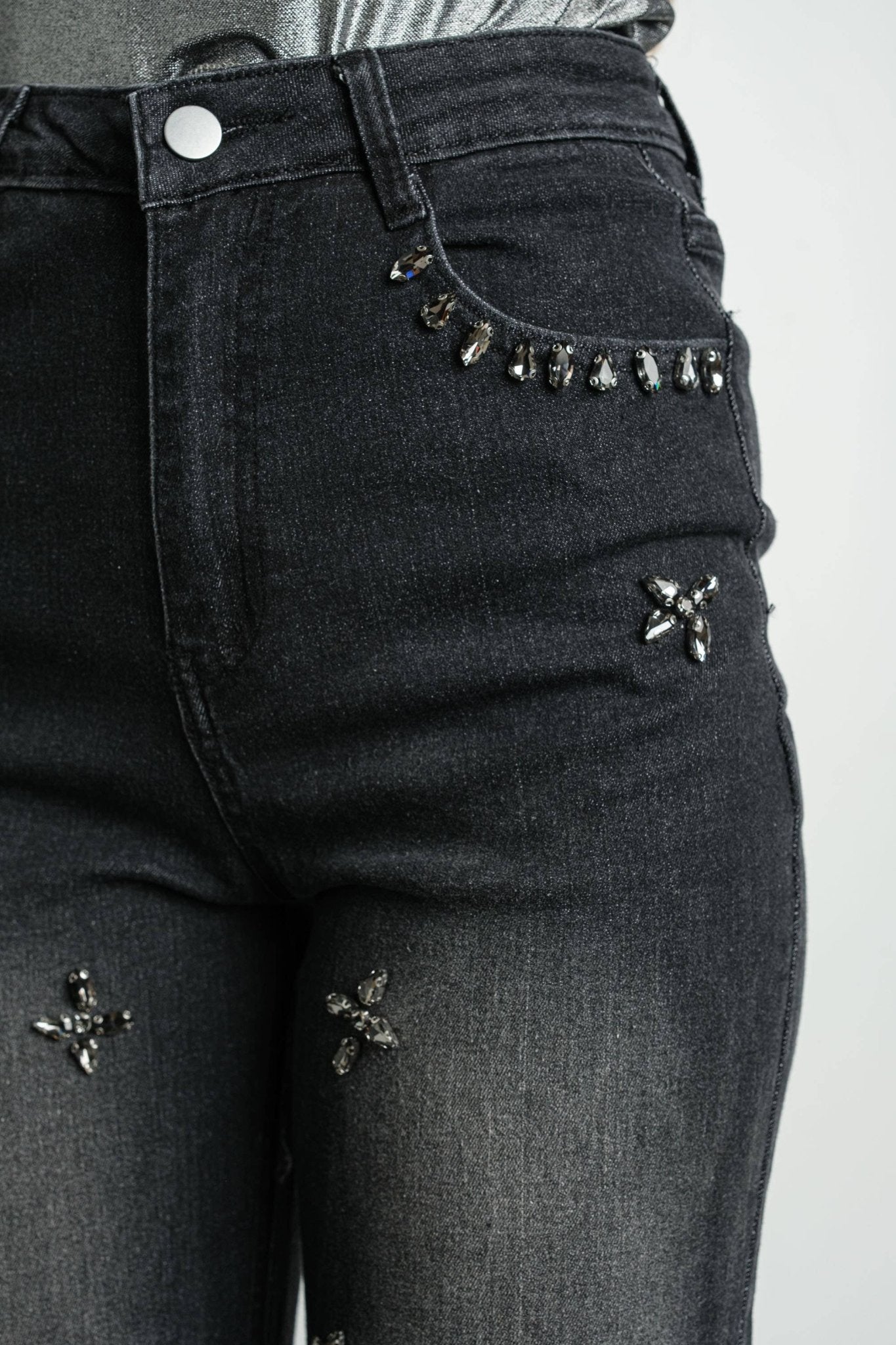 Close-up detail of gunmetal rhinestone embellishments on black wash denim jeans