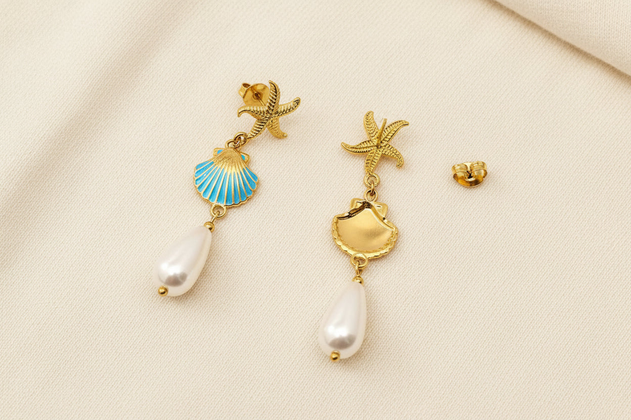 front and back view of coastal inspired gold earrings with gold starfish, enamal clam and pearl drop