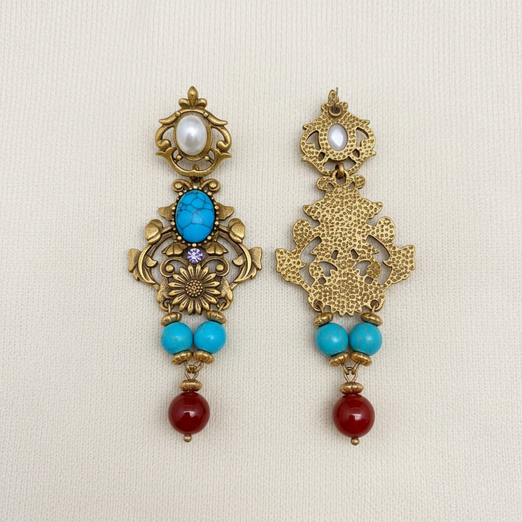 Ornate earrings with turquoise and red beads on an ivory background