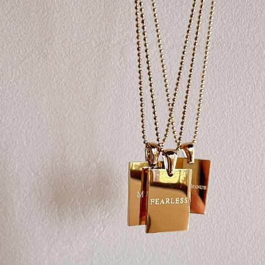 gold necklace with "fearless" engraved on it in front of a white background
