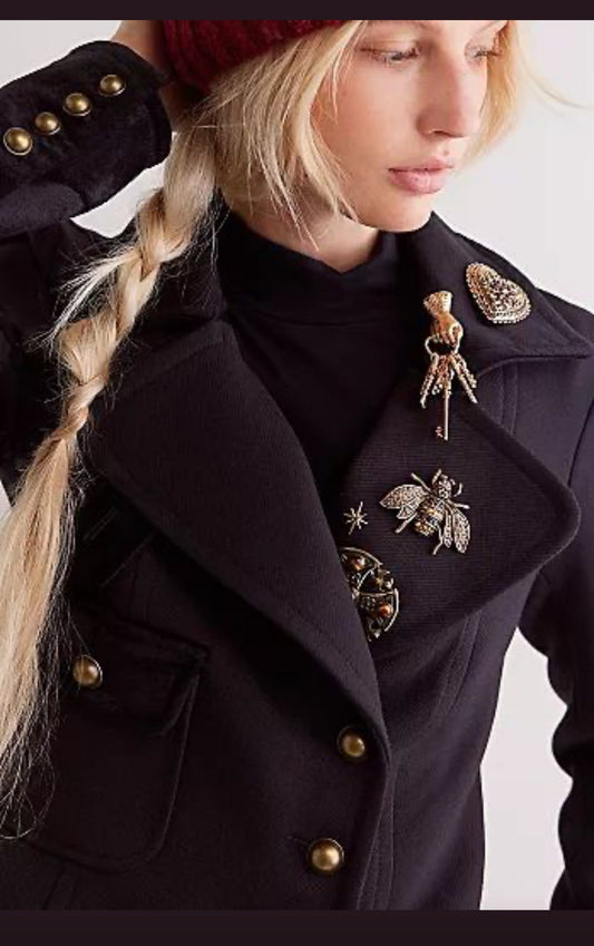 How to Modernize Vintage Brooches featuring a woman in a black coat with numerous brooches on her lapel