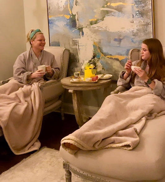 two women in robes lounging on chairs and blankets at a spa